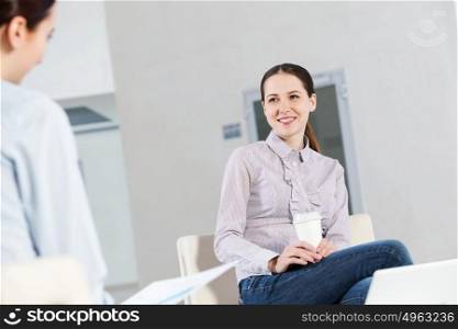Working in cooperation. Two young women sitting at office having conversation