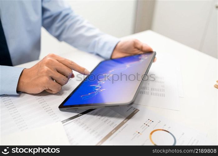 Working Man Conept The male employee sitting at his desk, holding a tablet, and touching the screen of his work.