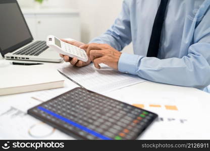 Working Man Conept The male officer sitting at his desk, holding the calculator, and pressing it.