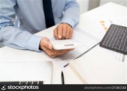 Working Man Conept The male officer sitting at his desk, holding the calculator, and pressing it.