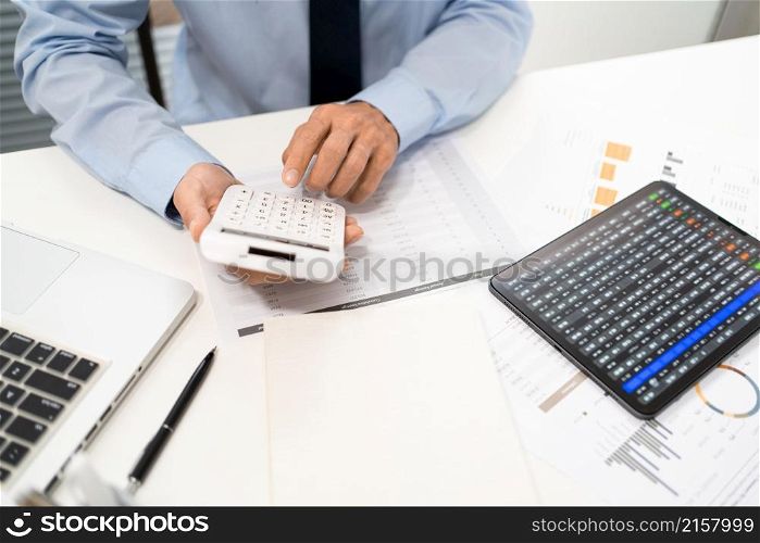 Working Man Conept The male officer sitting at his desk, holding the calculator, and pressing it.