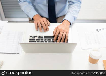 Working Man Conept The man in blue shirt with navy necktie sitting at his desk and typing letters on his notebook.