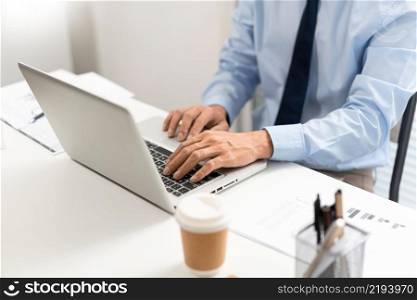 Working Man Conept The man in blue shirt with navy necktie sitting at his desk and typing letters on his notebook.