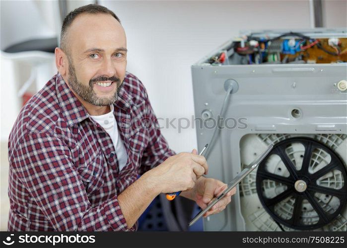 working man repairs a washing machine in laundry