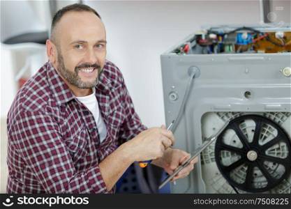 working man repairs a washing machine in laundry