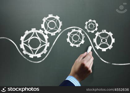 Working mechanism. Businessman hand drawing with chalk gears mechanism as teamwork concept