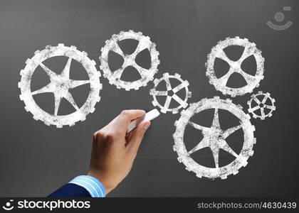 Working mechanism. Businessman hand drawing with chalk gears mechanism as teamwork concept