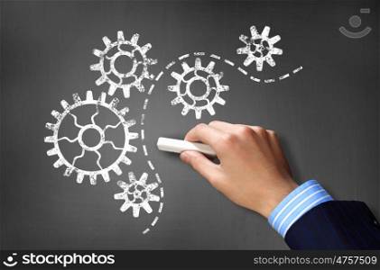 Working mechanism. Businessman hand drawing with chalk gears mechanism as teamwork concept