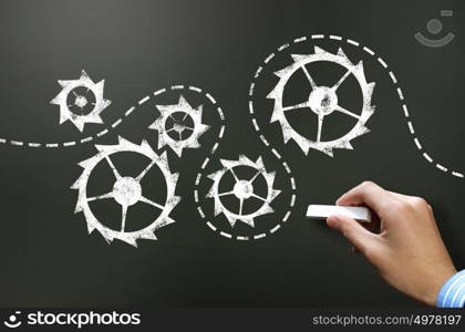 Working mechanism. Businessman hand drawing with chalk gears mechanism as teamwork concept