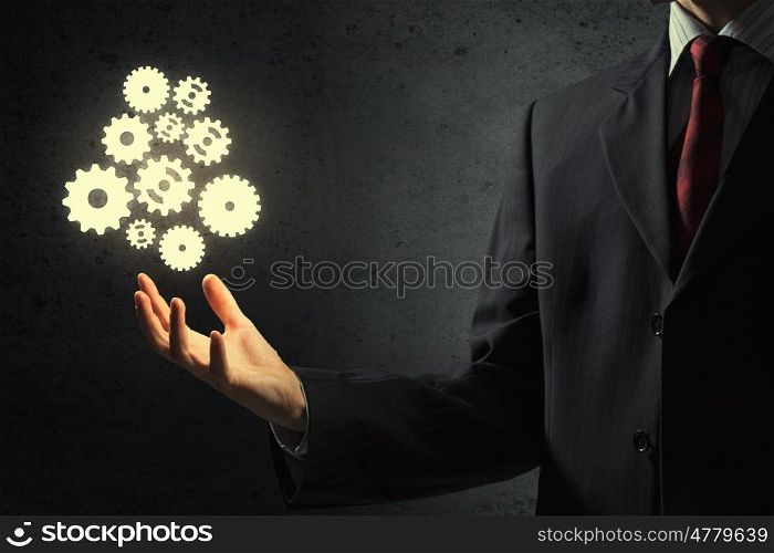 Working mechanism. Businessperson holding gears and cogwheels in palm
