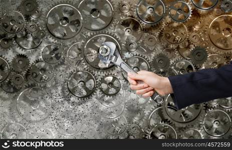 Working mechanism. Close up of businessman hand fixing mechanism with spanner