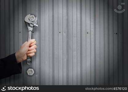 Working mechanism. Close up of businessman hand fixing mechanism with spanner