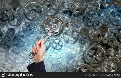 Working mechanism. Close up of businessman hand fixing mechanism with spanner