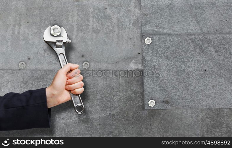 Working mechanism. Close up of businessman hand fixing mechanism with spanner