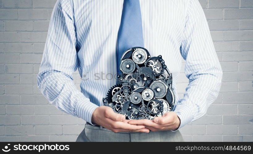 Working mechanism. Close up of businessman in suit holding metal gears in hands