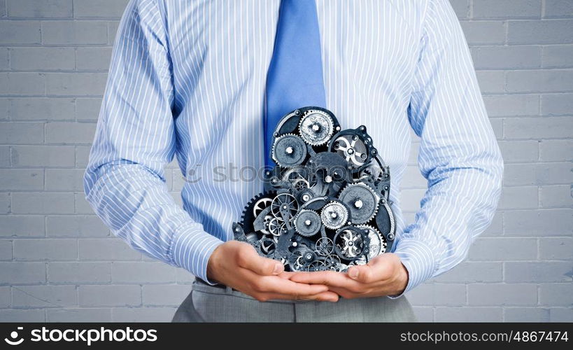 Working mechanism. Close up of businessman in suit holding metal gears in hands