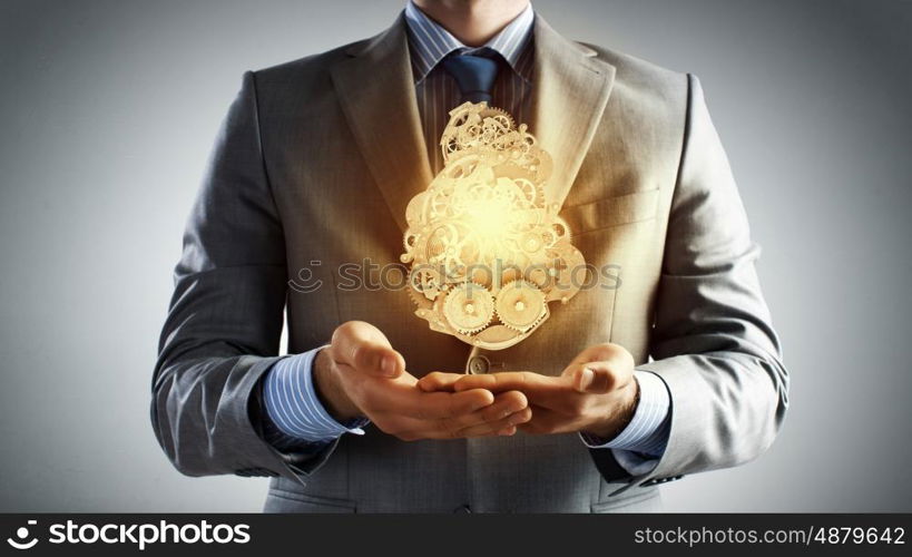 Working mechanism. Close up of businessman in suit holding metal gears in hands