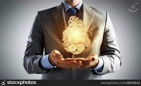 Working mechanism. Close up of businessman in suit holding metal gears in hands