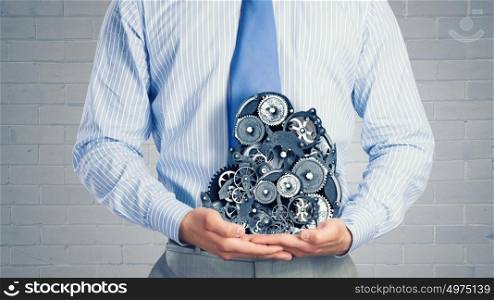 Working mechanism. Close up of businessman in suit holding metal gears in hands