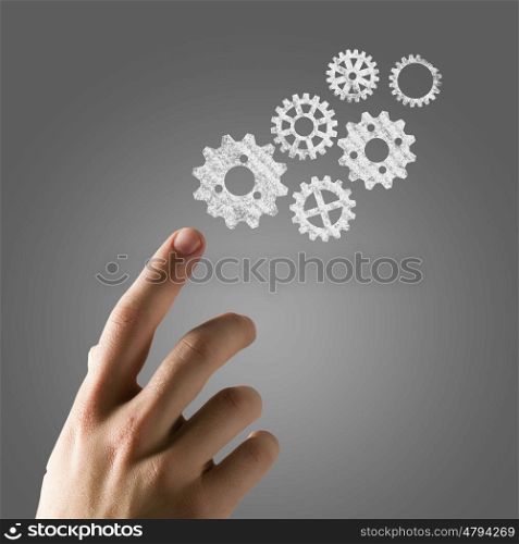 Working mechanism. Close up of hand and gears mechanism on gray background