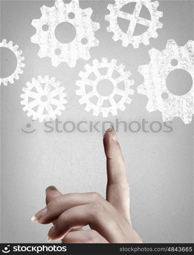 Working mechanism. Close up of hand and gears mechanism on gray background