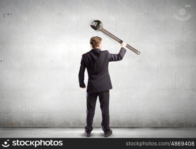 Working mechanism. Rear view of young businessman with wrench