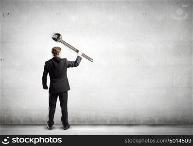 Working mechanism. Rear view of young businessman with wrench