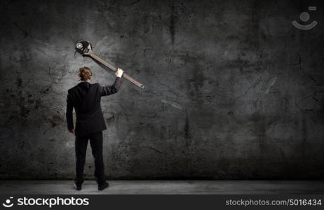 Working mechanism. Rear view of young businessman with wrench