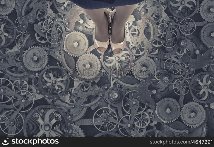 Working mechanism. Top view of businesswoman standing on floor of gears