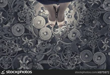 Working mechanism. Top view of businesswoman standing on floor of gears