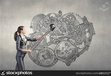 Working mechanism. Young businesswoman fixing gears mechanism with wrench