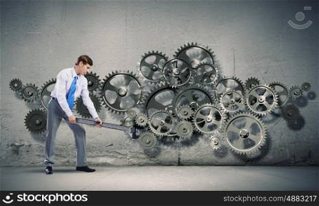 Working mechanism. Young determined businessman with wrench fixing mechanism