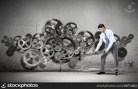 Working mechanism. Young determined businessman with wrench fixing mechanism