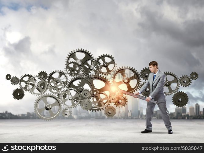 Working mechanism. Young determined businessman with wrench fixing mechanism