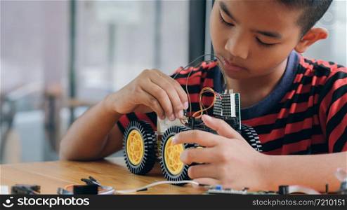 Working on Handmade car model, construction on electronic. Concentrated boy creating robot at lab. Early development, diy, innovation, modern technology concept.