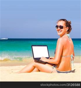 working on the beach. Woman is sitting with laptop with blank screen