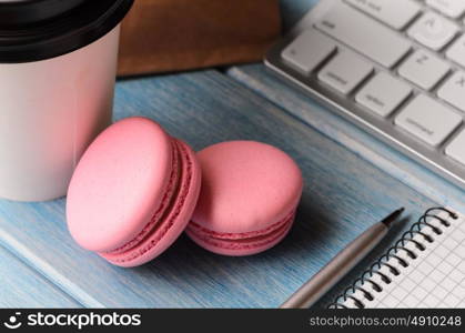 Working on the go. White modern keyboard with coffee cup, candies and notepad on blue wooden table at sunny weather