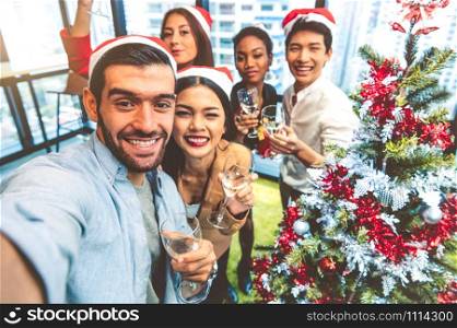 Working people self portrait of mixed race friends celebrating for Merry Christmas and Happy New Year party 2020 in working office. Multiracial diversity young business group selfie by phone camera
