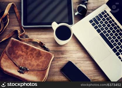 Working place: laptop, tablet, phone, cup of coffee and stylish bag on the table of a business woman, lifestyle of modern people concept