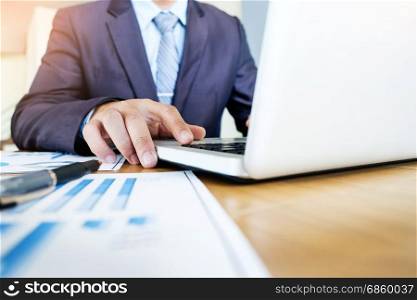 Working process startup. Businessman working with new finance project at office with laptop, tablet and graph data documents on his desk