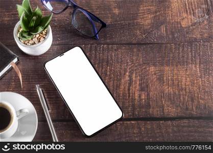 Working table with smart phone notepad coffee cup pen glasses plant on wooden table