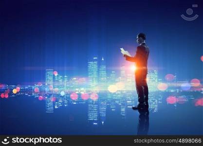 Working till late night. Young elegant businessman against night city background