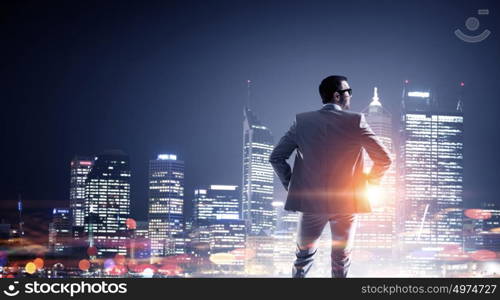 Working till late night. Young elegant businessman against night city background