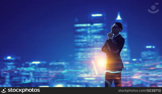 Working till late night. Young elegant businessman against night city background