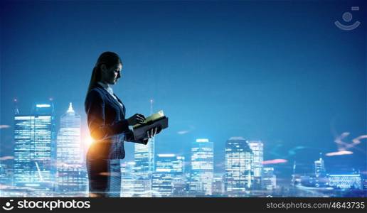 Working till late night. Young elegant businesswoman against night city background