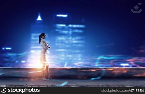 Working till late night. Young elegant businesswoman against night city background