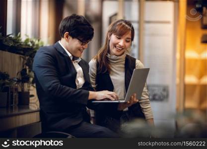 Working Together Concept. Smiling Two Business People of Man and Woman Workigng on Computer Laptop in Modern Workplace