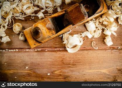 Working tool on wood on with shavings. On a wooden background. High quality photo. Working tool on wood on with shavings.