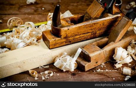 Working tool. Planer with wooden shavings. On a wooden background. High quality photo. Working tool. Planer with wooden shavings.