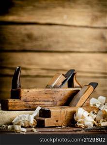 Working tool. Planer with wooden shavings. On a wooden background. High quality photo. Working tool. Planer with wooden shavings.